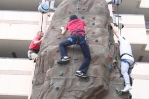 Nate Fermin/Courier Owner of Quantum Rock Fred Willis (left), Shawn Han 19 (mid), and Cam Duong 18 (right) attempt multiple levels of the rock wall featured in the middle of the PCC quad on September 3 2015. Quantum Rock and their rock wall tower over the quad for students to try for free.