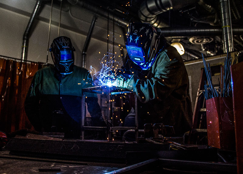 John Novak / Courier L to R. Joe Gonzales, teacher assistant, watches over Juan Hernandez as he perfoms MIG welding on a miniature table in the welding lab in room 137 of the Industrial Technologies buiding on Tuesday, April 9, 2013. MIG welding is the most popular type of welding because it is the most accessible and easiest weld to do.