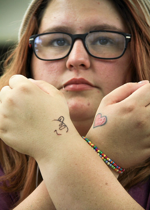 Mary Nurrenbern/Courier Myrna Koehling, nursing shows off two tattoos on her left and right hand on Nov 26, 2013 in the CC building. "The little heart is for family time and the smiley face is just because," said Koehling.